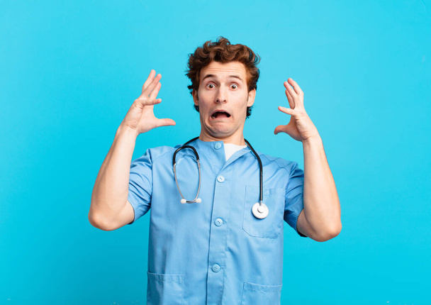 young nurse man screaming with hands up in the air, feeling furious, frustrated, stressed and upset - Photo, image