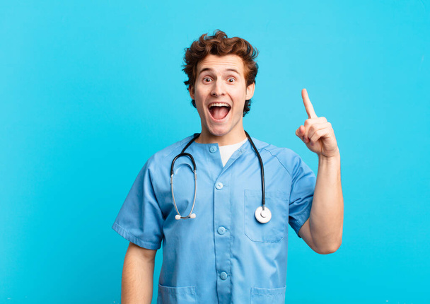 young nurse man feeling like a happy and excited genius after realizing an idea, cheerfully raising finger, eureka! - Valokuva, kuva