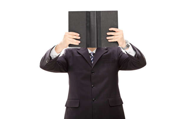 Businessman holding a book in front of his face  - Фото, изображение