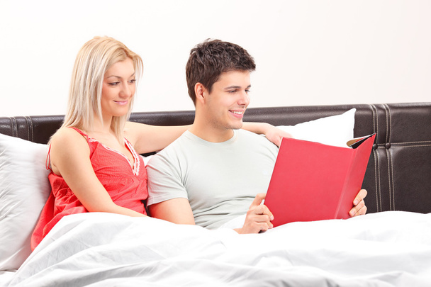 Couple on bed reading book - 写真・画像
