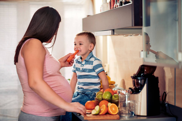 Pregnant woman and her son eating healthy vegetables. - Photo, Image