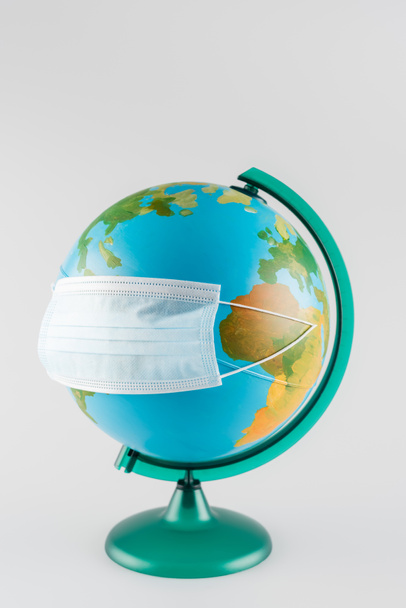 máscara protectora en globo terrestre aislado en gris, concepto de ecología - Foto, Imagen