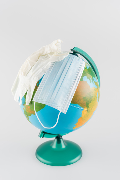 máscara médica y guantes de látex en globo aislado en gris, concepto de ecología - Foto, imagen