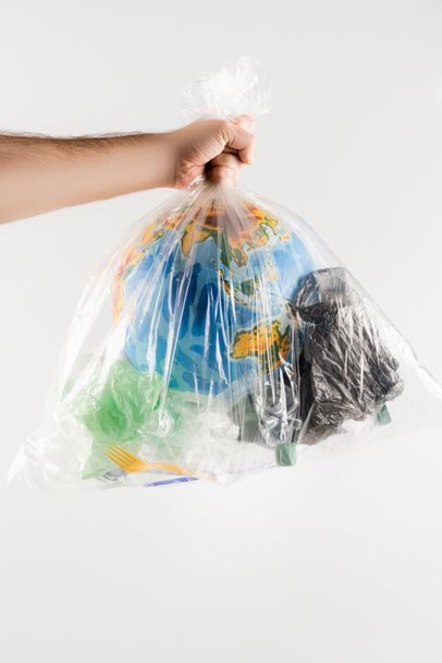 partial view of man holding plastic bag with garbage and globe isolated on grey, ecology concept - Photo, Image