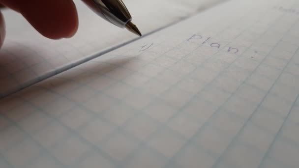 Mão com caneta azul sobre caderno quadriculado com plano de palavras. - Filmagem, Vídeo
