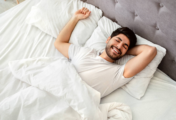 Bem dormido árabe homem acordando e sorrindo, desfrutando de bom dia na cama - Foto, Imagem