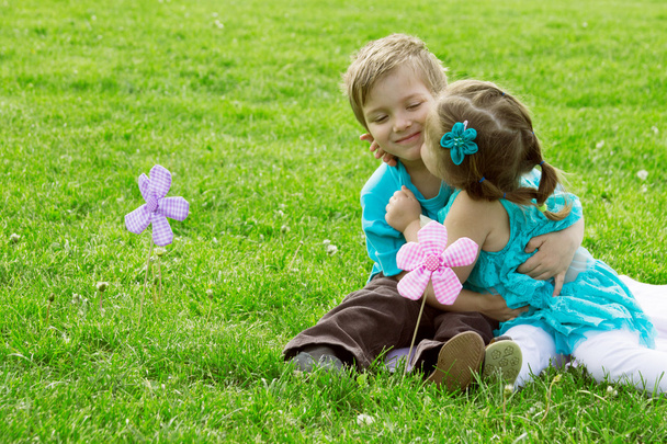 Маленький хлопчик і дівчинка цілуються в зеленій траві
 - Фото, зображення