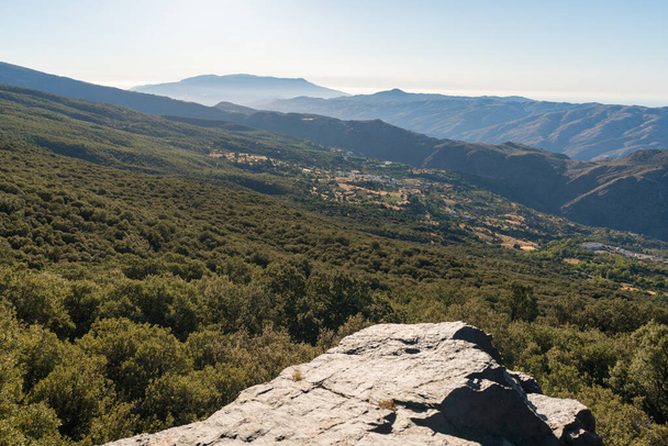 Hegyvidéki táj Sierra Nevadában Dél-Spanyolországban, két falu van a hegyoldalon, fenyőerdők és bokrok, az ég tiszta - Fotó, kép