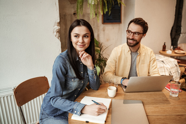 freelancer en gafas usando laptop y mirando a la mujer en la cafetería - Foto, imagen