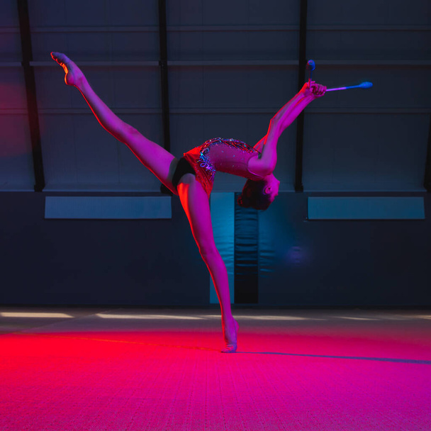 Jovem ginasta rítmica feminina isolada em fundo multicolorido em luz de néon - Foto, Imagem