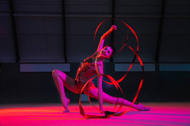 Genç bayan ritmik jimnastikçi, çok renkli arka planda, neon ışıkta izole edilmiş. - Fotoğraf, Görsel