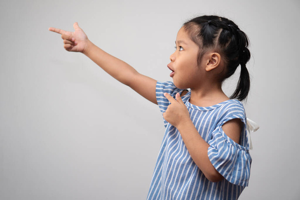 Портрет азиатского ребенка и собирать волосы и Положите указательный палец к воздуху и сделать мышление взволнованной позы на изолированном белом фоне, она счастье, сияние в молодости, концепция образования - Фото, изображение