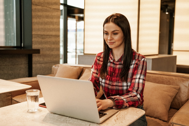 brunette freelancer using laptop while working remotely in cafe - Photo, Image