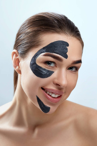 Beauty Face Mask. Skin care face Spa treatment . Beautiful Young Woman with black mask of clay on face. Moisturizer Mask. - Fotografie, Obrázek