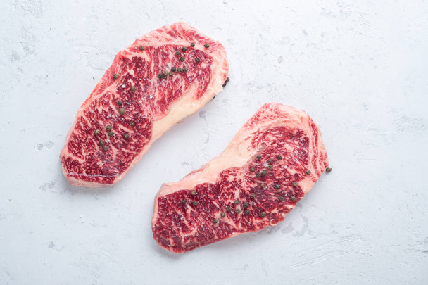 Fresh marbled beef steaks with salt and pepper prepared for grilling - Photo, Image