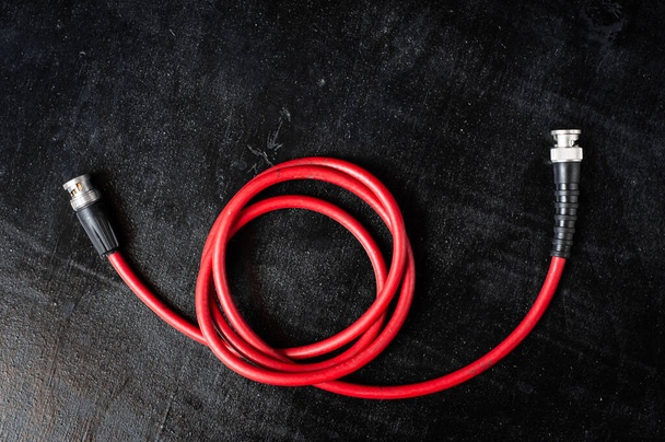 Cable rojo para transferir señal sdi a través del conector bnc sobre un fondo oscuro - Foto, imagen