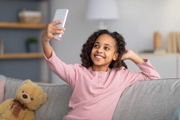 Щаслива дівчина-підліток бере селфі для соціальної мережі, тримає смартфон в руці, знімає вдома
 - Фото, зображення