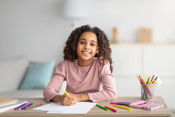 Glückliches schwarzes Schulmädchen zeichnet Bild zu Hause - Foto, Bild