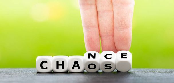 Hand turns dice and changes the word chaos to chance. - Photo, Image