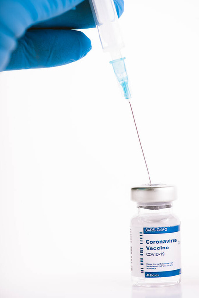 Ręce z niebieskimi rękawiczkami lateksowymi, strzykawka z fiolką zawierającą szczepionkę przeciw zakaźnemu wirusowi - Zdjęcie, obraz