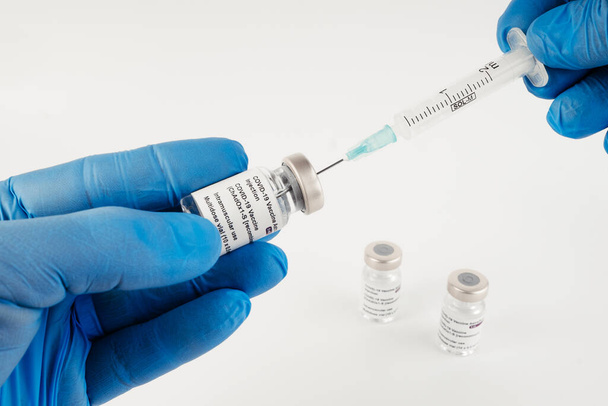 Niebieskie rękawiczki z trzema fiolkami zawierającymi szczepionkę Covid-19 o białym tle i strzykawką do wstrzykiwań dla personelu medycznego i osób zagrożonych. Przestrzeń kopiowania. - Zdjęcie, obraz