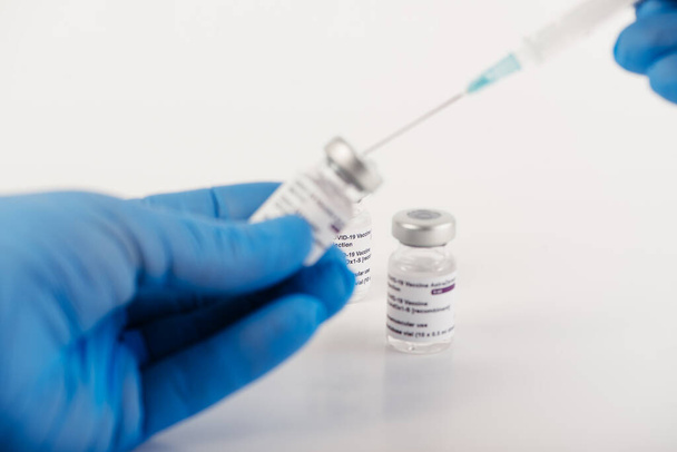 Gants bleus avec trois flacons de vaccin Covid-19 à fond blanc et une seringue pour injecter des professionnels de la santé et des personnes à risque. Espace de copie. - Photo, image