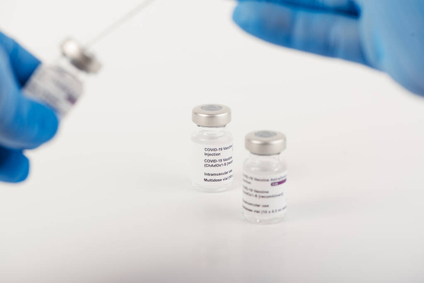 Kék kesztyű három, fehér hátterű Covid-19 vakcinát tartalmazó injekciós üveggel és egy fecskendővel az egészségügyi szakemberek és a veszélyeztetett személyek befecskendezésére.SARS-CoV-2 oltási kezelés. Fénymásolási hely. - Fotó, kép