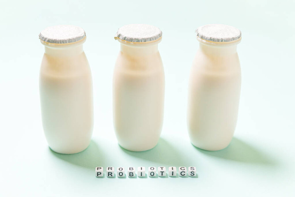 プロバイオティクスとプレバイオティクスの乳製品が入った小さなボトルは青色の背景で飲む。生物学的に活性な添加物で生産。発酵と食事の健康的な食品。有用微生物とのバイオヨーグルト - 写真・画像