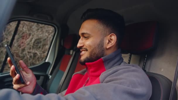 Genç Hintli adam minibüste oturuyor ve telefonla konuşuyor. - Video, Çekim