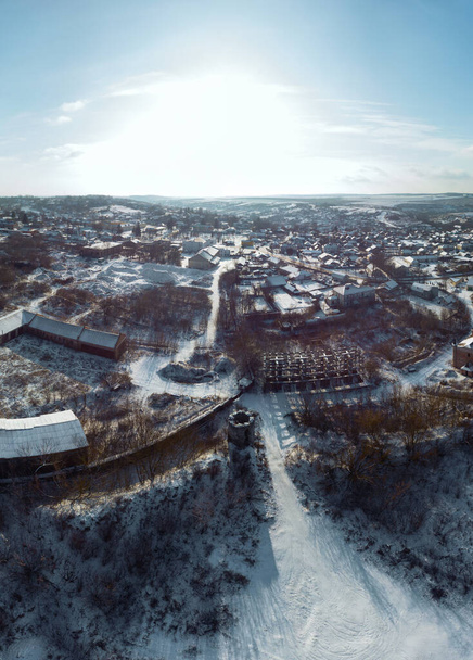 Aerial vertical view of ruins of an ancient fortress, view of the village. Snow and winter. river and forest. Sataniv, Ukraine - Photo, Image