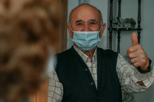 starší muž v masce s palcem pozvednutým v pozitivním pořádku znamení - Fotografie, Obrázek