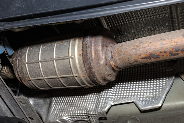 Ein Dieselpartikelfilter in der Auspuffanlage eines Autos auf einem Aufzug in einer Kfz-Werkstatt, von unten gesehen. - Foto, Bild