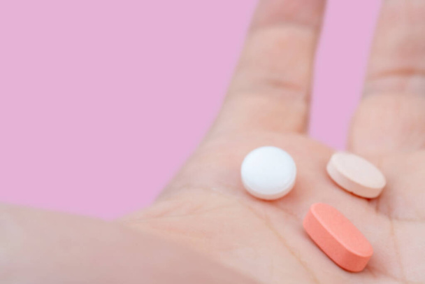 Pillole bianche e rosa nel palmo della mano. Trattamento con pillole.  - Foto, immagini