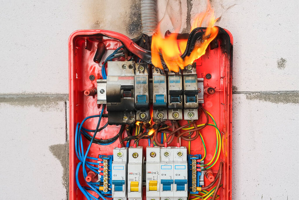 Burning switchboard from overload or short circuit on wall closeup - Photo, Image