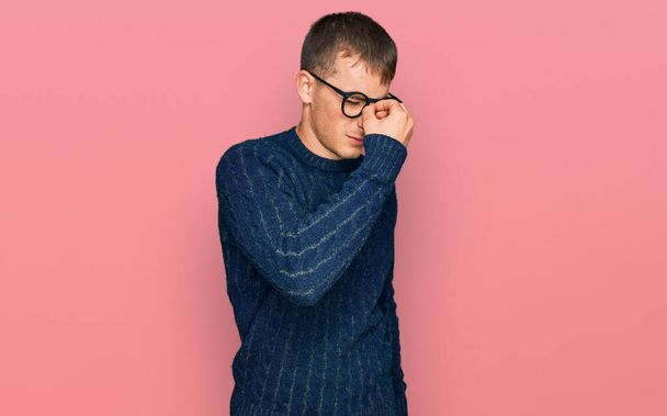 Young blond man wearing casual clothes and glasses tired rubbing nose and eyes feeling fatigue and headache. stress and frustration concept.  - 写真・画像