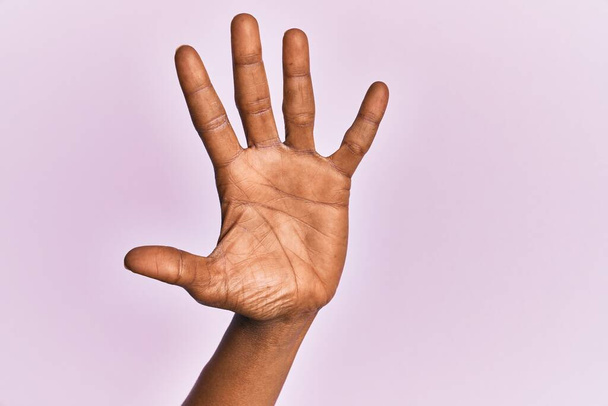 Χέρι και χέρι της μαύρης μεσήλικας γυναίκα πάνω από ροζ απομονωμένο φόντο καταμέτρηση αριθμό 5 δείχνει πέντε δάχτυλα  - Φωτογραφία, εικόνα