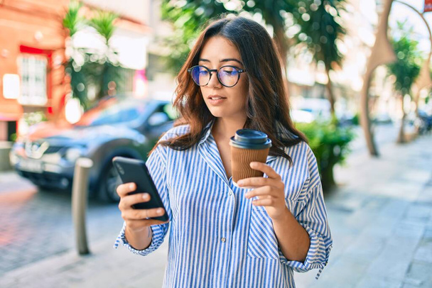 Young hispanic businesswoman with serious expression using smartphone at the city. - Foto, afbeelding