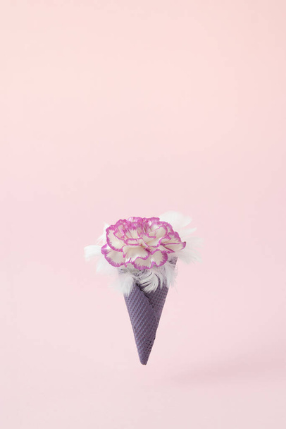 Frühling kreative Bouquet von Nelken in Eiscreme lila Kegel auf dem pastellrosa Hintergrund, Minimales Konzept mit Kopierraum. - Foto, Bild