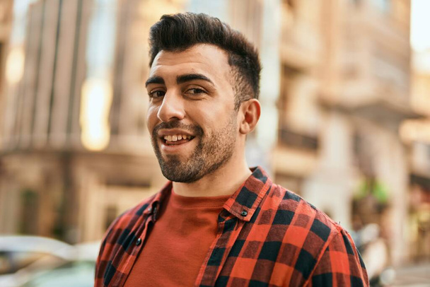 Mladý hispánec se šťastně usmívá, když stojí ve městě. - Fotografie, Obrázek