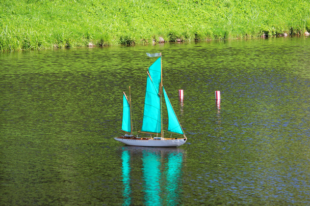 kleines türkisfarbenes Segelboot auf dem See, ferngesteuert - Foto, Bild