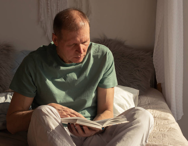 Mature man reading book. Mature person on bed resting. - Photo, Image