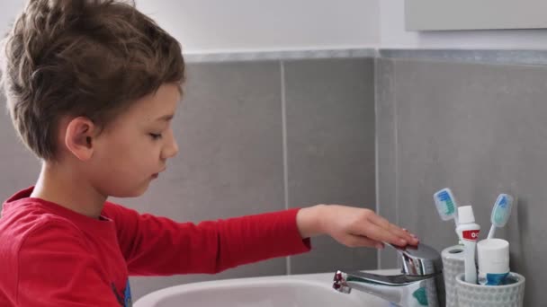 chłopiec myjący zęby nad zlewem - Materiał filmowy, wideo