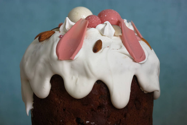 Gâteau de Pâques décoré de glaçage blanc, meringue, boules de chocolat décoratives roses, noix. Pain de Pâques maison vue sur le dessus sur fond bleu. Une recette pour un gâteau de Pâques traditionnel. - Photo, image