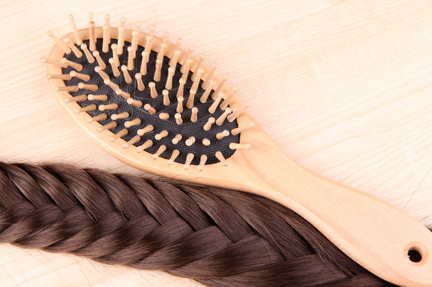 Long brown hair with hairbrush on wooden background - Fotografie, Obrázek