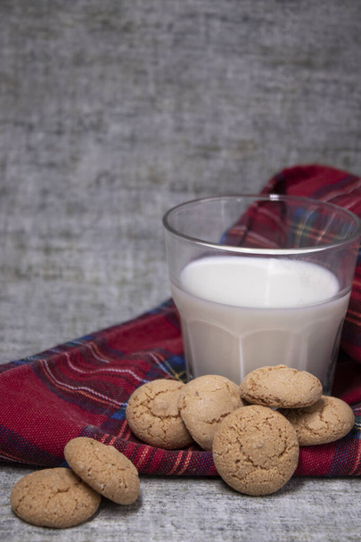 sklenice mléka u mandlových amaretti sušenek na plátované červené ubruse. zdravé snídaně svačinka. - Fotografie, Obrázek