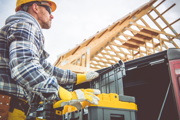 Arbeiter eines Bauunternehmens bereitet sich auf einen weiteren Tag im Baugewerbe vor und checkt seine Werkzeugkästen vor dem Bauwerk. - Foto, Bild