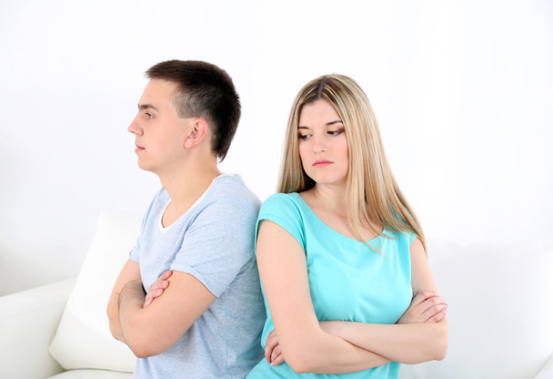 Young man and woman  conflict sitting on sofa argue unhappy, on home interior background - 写真・画像