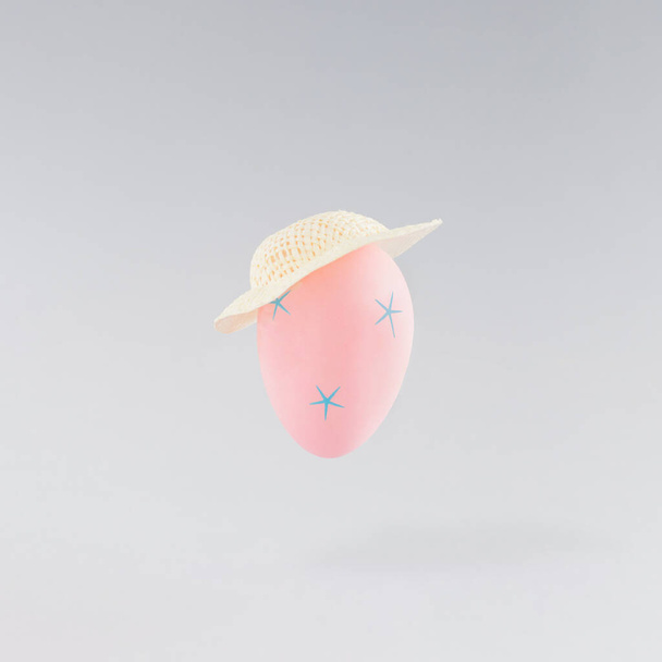 Composición creativa con huevo de Pascua rosa y sombrero sobre un fondo gris. Mínimo concepto de vacaciones de primavera. Fondo de pastel. - Foto, Imagen