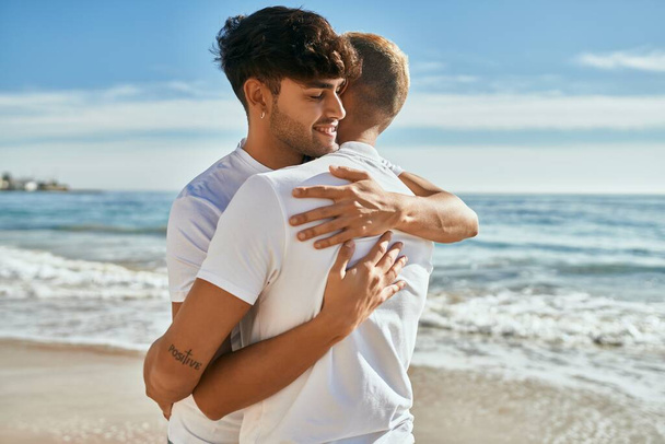 Jeune couple gay souriant heureux étreinte à la plage. - Photo, image