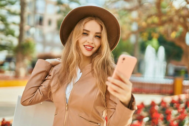 Young blonde girl shopping using smartphone at the city. - Foto, Bild